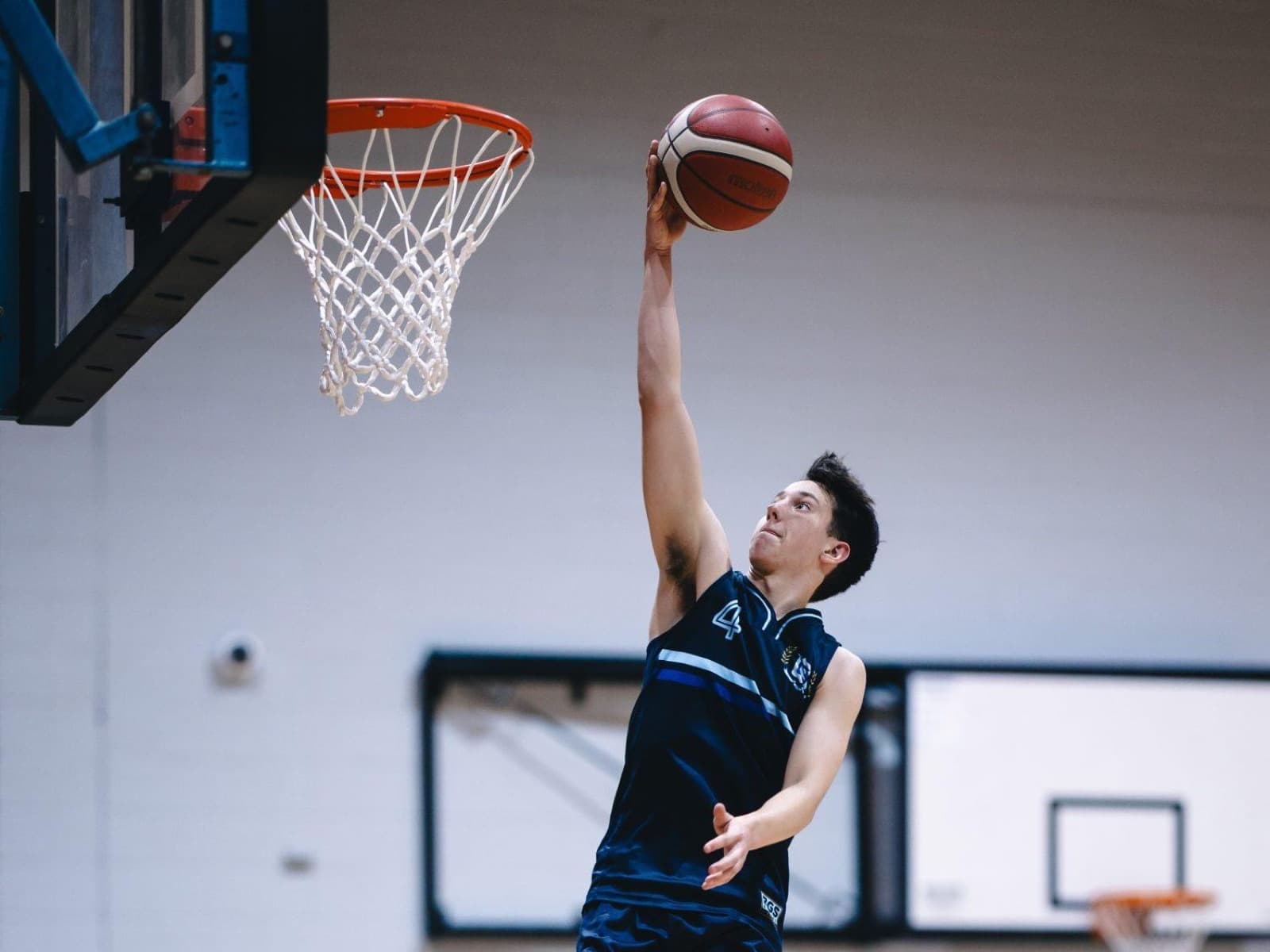 Brisbane Grammar School player finishing at the rim in a school basketball game