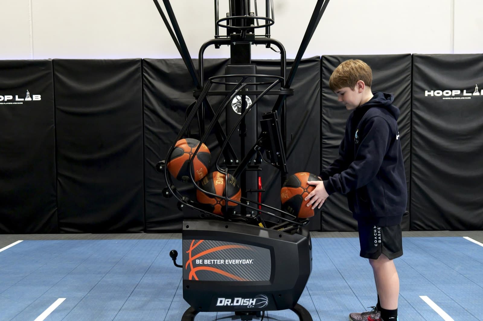 Junior player loading basketballs into the Dr. Dish CT+ at HoopLab