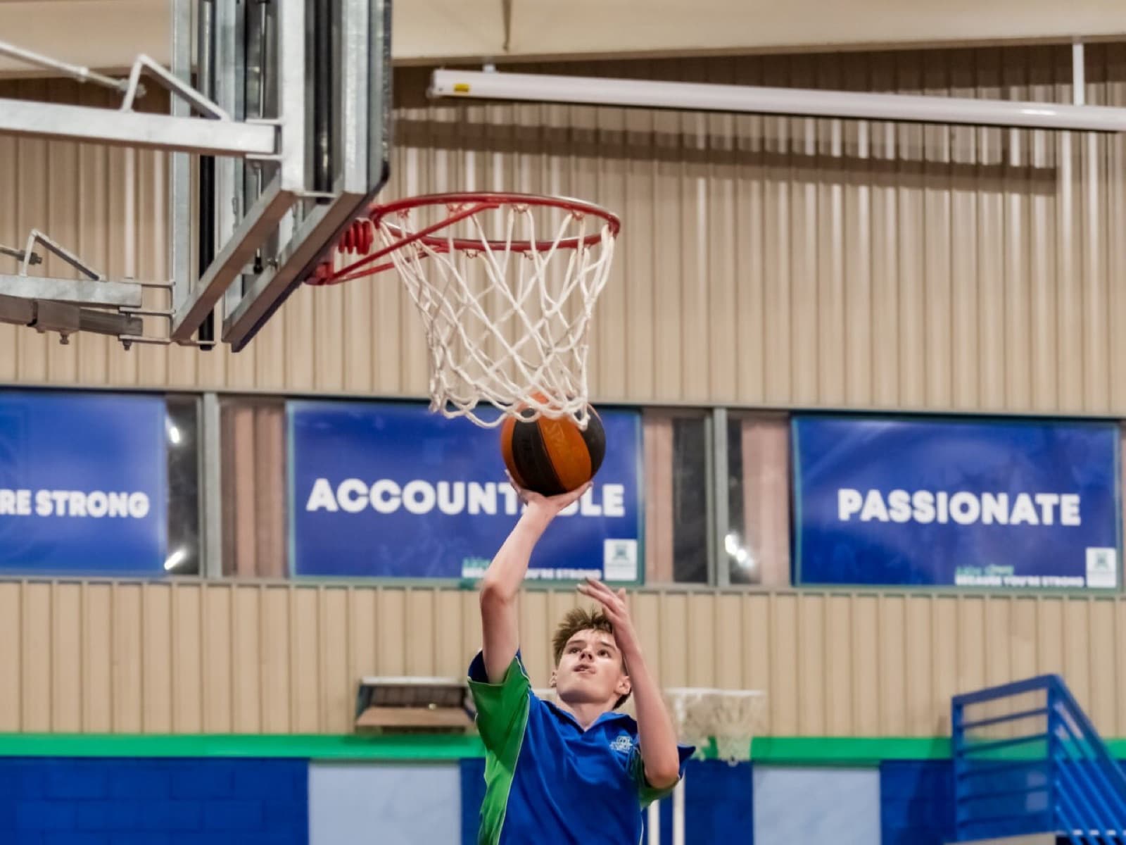 Modbury High School student reaching for the rim in the school gym