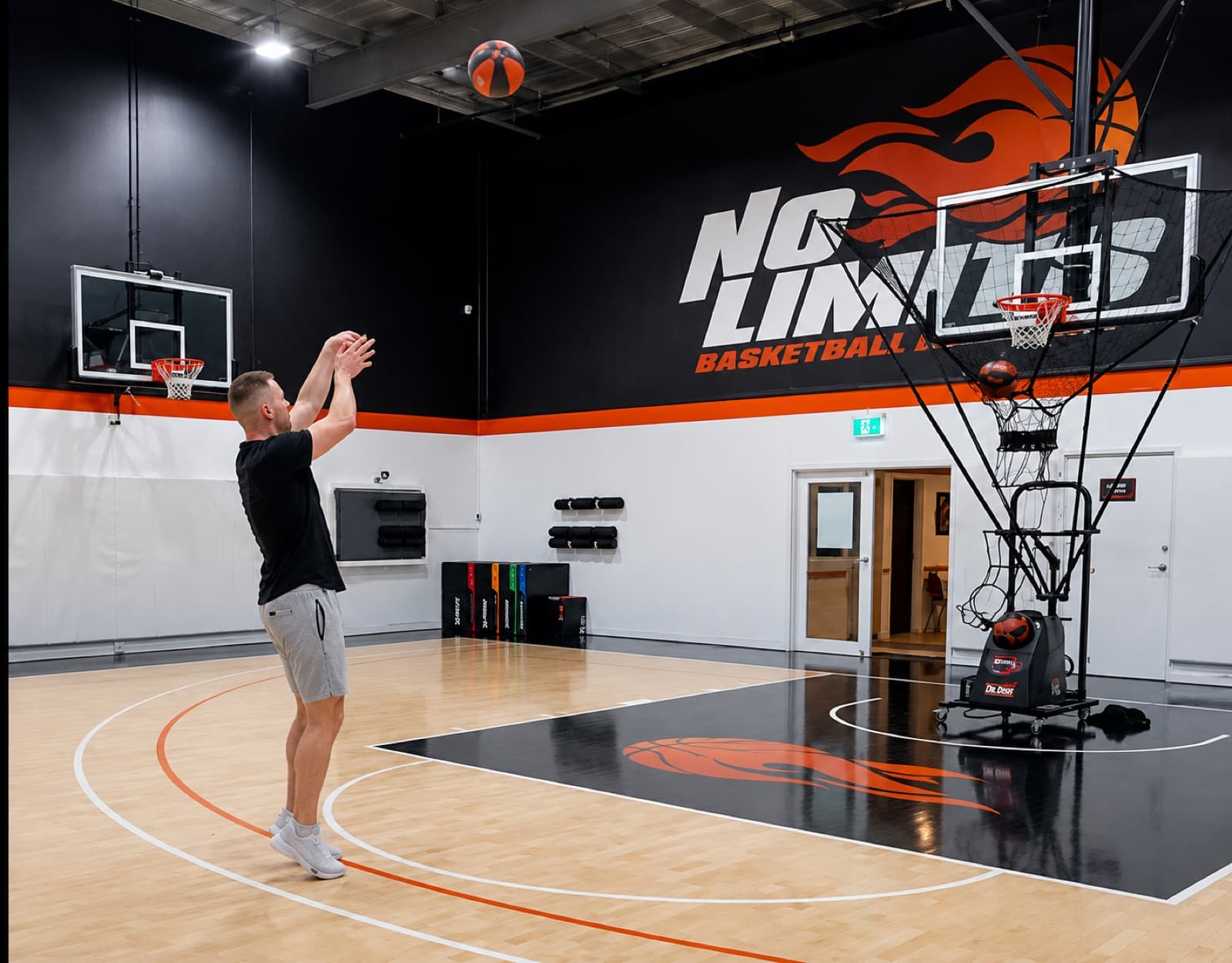 Shooter working on form under the No Limits Basketball mural, with a Dr. Dish machine behind