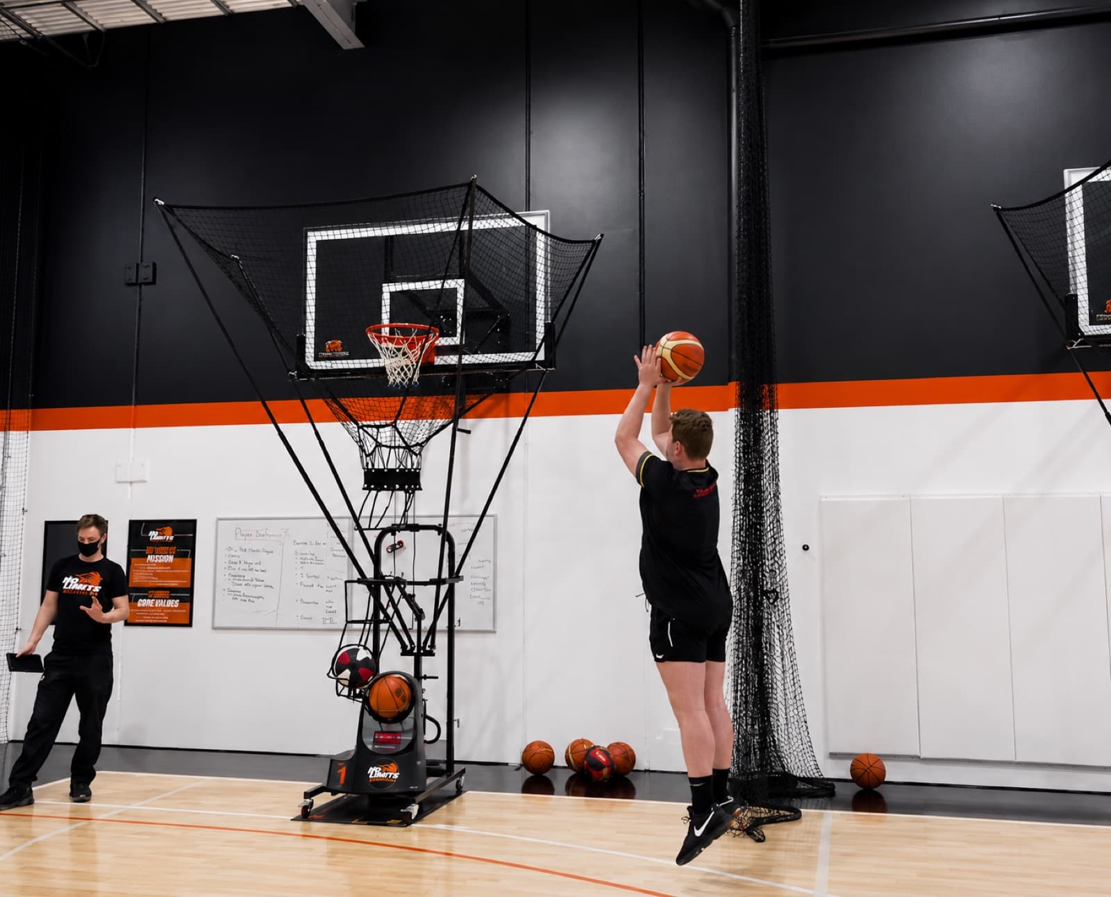 Coach watching a player shoot on a Dr. Dish machine at No Limits Basketball